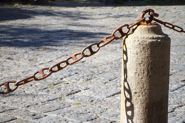 Close-up van een stenen hek pijler en ketting op een stenen stoep achtergrond — Stockfoto