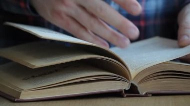 Rusça bir kitap boyunca yapraklı bir adam elinin yakın çekim, sayfaların arasında parmaklarını çalıştıran, malzemeyi inceleyen, seçici odaklama