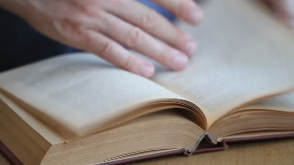 Gros plan d'une main d'homme feuilletant un livre en russe, passant ses doigts à travers les pages, étudiant la matière, se concentrant sélectivement 