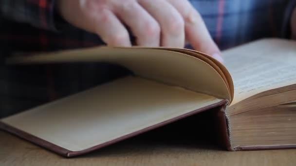 Gros plan d'une main d'homme feuilletant un livre en russe, passant ses doigts à travers les pages, étudiant la matière, se concentrant sélectivement 