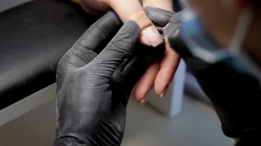 Güzellik uzmanı güzellik salonunda manikür için tırnak çubuğu öğütür. Tırnak tedavisi, taşlama ve parlatma.