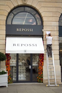 Merdivenlerdeki bir adam Paris'teki Place Vendome'daki Repossi mağazasının girişini onarıyor.