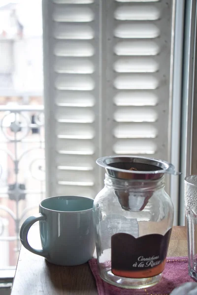 금속 셔터가 달린 창문에 뜨거운 커피와 유리 병 한 잔. — 스톡 사진