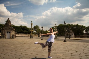 Paris'teki Place de la Concorde'da mutlu bir şekilde dans eden kız.