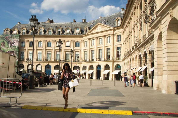 İnsanlar butiklerde yürüyüp Paris'teki Place Vendome'da yürüyüşe çıkıyorlar.