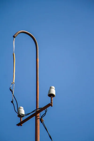 Pólo elétrico velho com isoladores cerâmicos e fios sobre um céu azul, foco seletivo — Fotografia de Stock