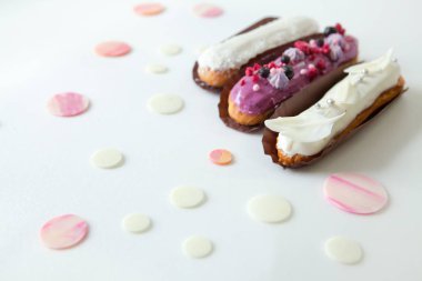 Farklı dolgular ve tasarım beyaz çikolata damlaları ile dekore edilmiş beyaz bir yüzey üzerinde izole ile üç eclairs bir dizi