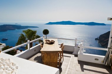 Santorini Adası, Yunanistan 'da lüks bir otelde masa ve sandalyeler ile deniz manzaralı Teras