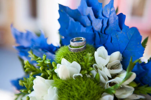 Beyaz ve yeşil renklerde düğün buketi ve beyaz bir yüzey üzerinde mavi dekorasyon alyans — Stok fotoğraf