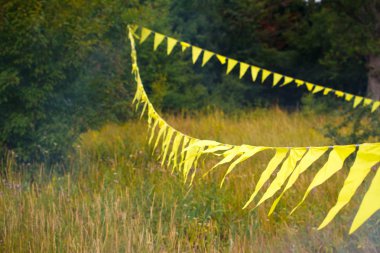 Üçgen sarı bayraklar dekorasyon orman yakınındaki çimenli bir çayır boyunca gerilmiş