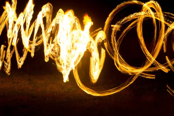 Artysta pokazuje pokaz ognia w nocy Spinning latarki, okręgi ognia i pętle — Zdjęcie stockowe