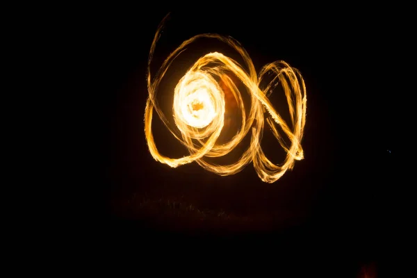 Der Künstler zeigt eine Feuershow bei Nacht, bei der Fackeln, Feuerkreise und Schleifen gesponnen werden — Stockfoto