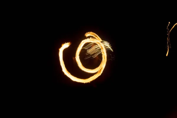 O artista mostra um show de fogo à noite girando tochas, círculos de fogo e loops — Fotografia de Stock
