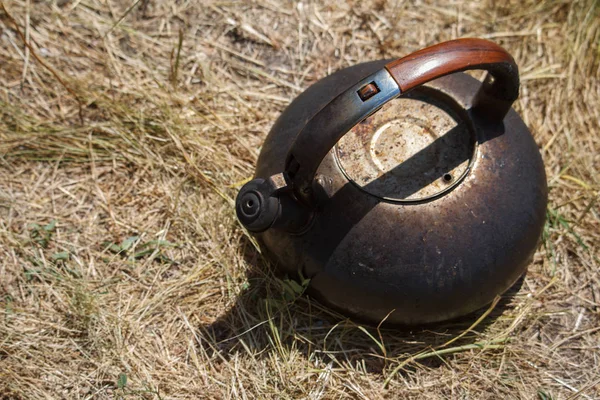 Close-up gerookte metalen ketel staande op het droge gras in de buurt van de vreugdevuur — Stockfoto