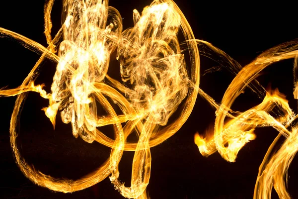 Konstnären visar en eldshow på natten spinning facklor, cirklar av eld och loopar — Stockfoto