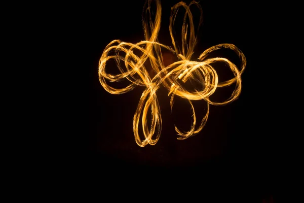 O artista mostra um show de fogo à noite girando tochas, círculos de fogo e loops — Fotografia de Stock