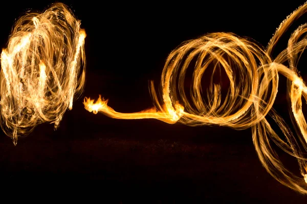 O artista mostra um show de fogo à noite girando tochas, círculos de fogo e loops — Fotografia de Stock