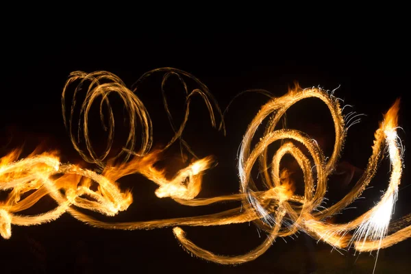 De kunstenaar toont een vuurshow 's nachts draaiende toortsen, cirkels van vuur en lussen — Stockfoto