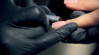 Sürecinde profesyonel çivi bakımı, siyah eldiven kozmetik polygel kapaklı bir manikür için çivi kadın müşteri yapma
