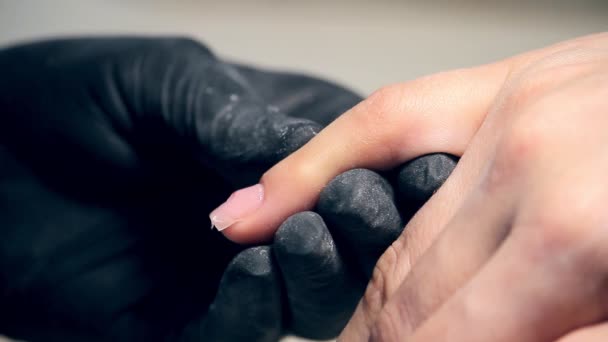 Professionele nagels zorg in proces, schoonheidsspecialist in zwarte handschoenen maken nagels vrouwelijke klant voor een manicure met polygel cover — Stockvideo