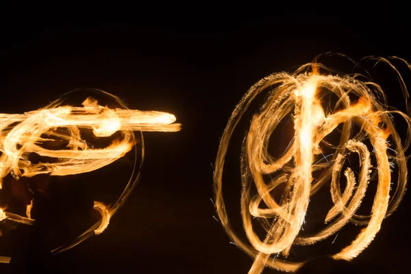 El artista muestra un espectáculo de fuego en la noche girando antorchas, círculos de fuego y bucles —  Fotos de Stock