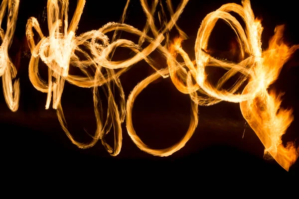El artista muestra un espectáculo de fuego en la noche girando antorchas, círculos de fuego y bucles —  Fotos de Stock