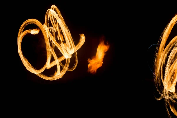 De kunstenaar toont een vuurshow 's nachts draaiende toortsen, cirkels van vuur en lussen — Stockfoto