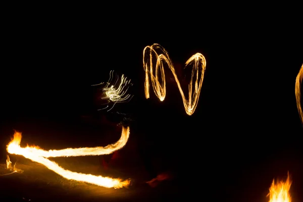 Der Künstler zeigt eine Feuershow bei Nacht, bei der Fackeln, Feuerkreise und Schleifen gesponnen werden — Stockfoto