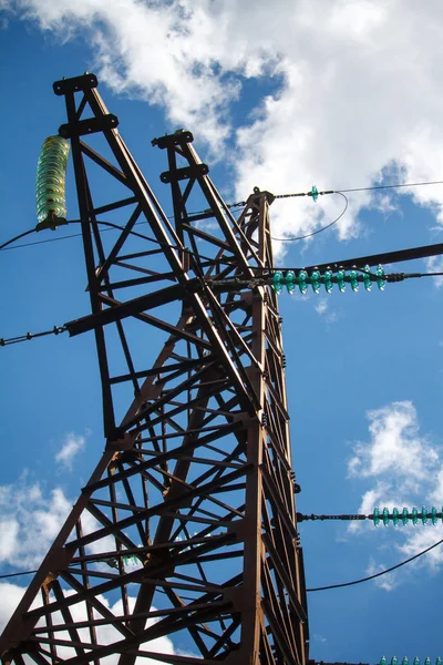 Vista inferior de um poste de metal de uma linha de energia com uma infinidade de fios elétricos contra um céu azul nublado — Fotografia de Stock