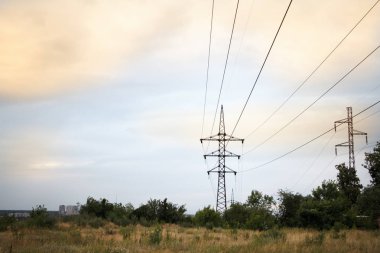 Buğday biçilmiş bir alanın arka planına karşı birkaç güçlü güç hatları ve bulutlu bir günbatımı gökyüzü, yumuşak odak ile Manzara