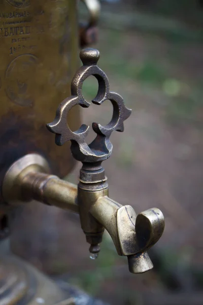 Grifo elegante de cerca de un viejo samovar de cobre sobre un fondo borroso del bosque, enfoque selectivo — Foto de Stock