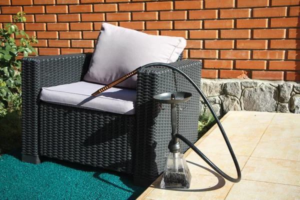 Sedia in vimini nero con cuscini grigi e narghilè pronto per fumare sono sulla terrazza estiva — Foto Stock
