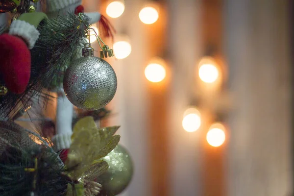 Gros plan jouets brillants suspendus sur un arbre de Noël sur le fond de lumières floues de guirlande, mise au point sélective — Photo