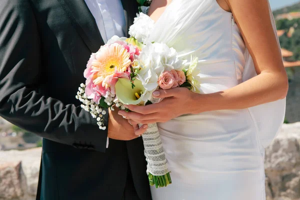 Крупным планом новобрачные обнимаются и держат свадебный букет в руках, избирательный фокус — стоковое фото