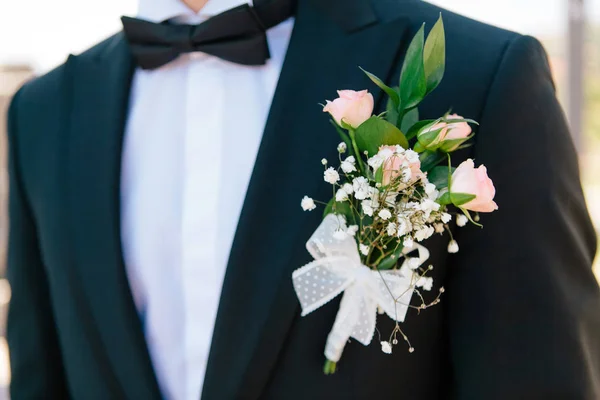 Primer plano rosas rosadas boutonniere con la decoración de un novio azul oscuro elegante chaqueta, enfoque selectivo — Foto de Stock