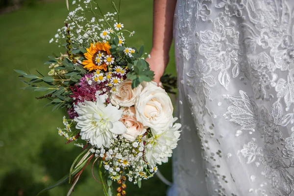 Η νύφη κρατά ένα μπουκέτο φρέσκο άνοιξη και το καλοκαίρι λουλούδια σε παστέλ χρώματα σε θολή φόντο, επιλεκτική εστίαση — Φωτογραφία Αρχείου