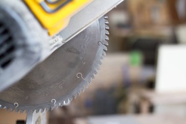 Yakın çekim sabit dairesel testere bir maranyesiz masasında bir marandülhane Atölyesi, seçici odak bulanık bir arka plan üzerinde