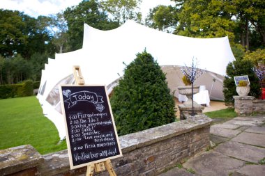 Konuklar için düğün pavilyonu ve düğün etkinliklerinin yazılı programı ile siyah bir tahta, seçici odak