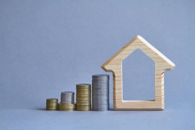 Gri arka planda yakın sikke birkaç sütun ile evin bir ahşap heykelcik, satın alma veya bir bina Kiralama kavramı, seçici odak