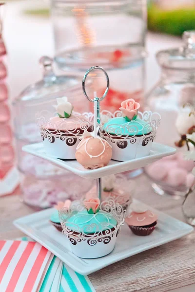 Gros plan de cupcakes multicolores sur de nombreux piédestaux prêts pour un pique-nique, un buffet ou une cérémonie de mariage à l'extérieur, focus sélectif — Photo