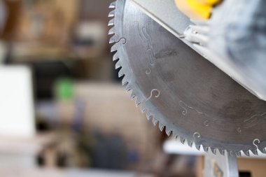 Yakın çekim sabit dairesel testere bir maranyesiz masasında bir marandülhane Atölyesi, seçici odak bulanık bir arka plan üzerinde