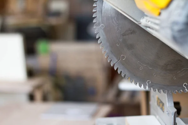 Close-up stationary circular saw on a carpentry table on a blurred background of a carpentry workshop, selective focus