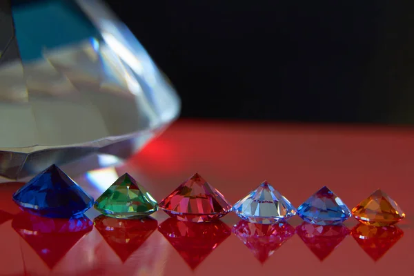 Riesiger Diamant und mehrere schicke Kristalle auf roter und schwarzer Oberfläche, schimmern und funkeln — Stockfoto