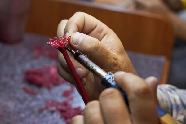 Close-up of a master jeweler surfacing wax blanks of jewelry on a tree before laying in a flask, selective focus