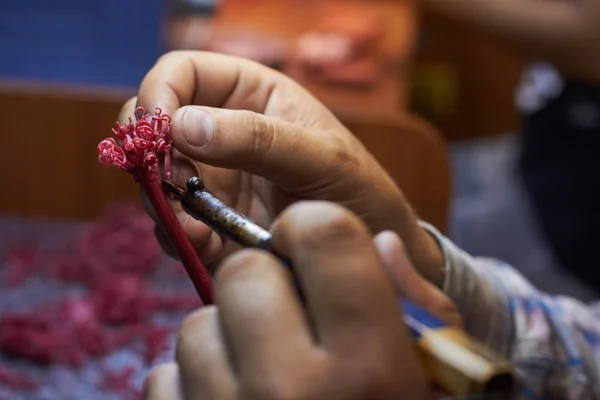 Close-up of a master jeweler surfacing wax blanks of jewelry on a tree before laying in a flask, selective focus