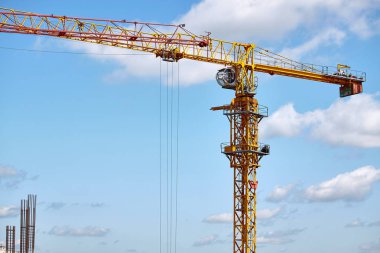 Yüksek katlı bir binanın inşası, kule vinçlerinin mavi gökyüzüne karşı çalışması, seçici odak