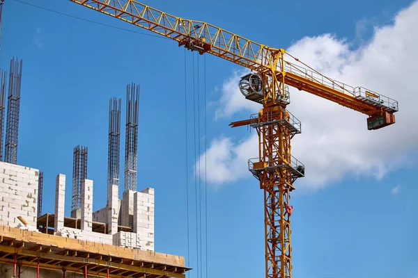 Construcción de un edificio de gran altura, la formación de soportes de cemento y el funcionamiento de una grúa contra un cielo azul, enfoque selectivo — Foto de Stock