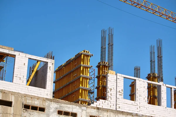 Construcción de un edificio de gran altura, la formación de soportes de cemento y el funcionamiento de una grúa contra un cielo azul, enfoque selectivo — Foto de Stock