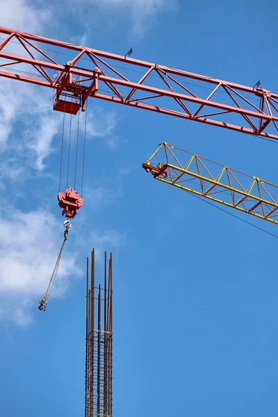 Close-up of two arrows of construction cranes arranged in parallel against a blue sky, selective focus