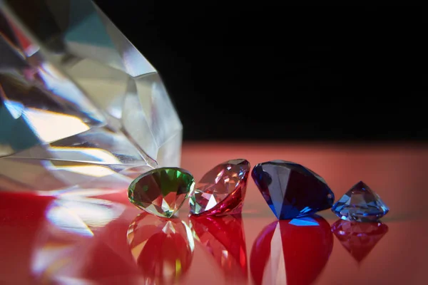 Riesiger Diamant und mehrere schicke Kristalle auf roter und schwarzer Oberfläche, schimmern und funkeln — Stockfoto
